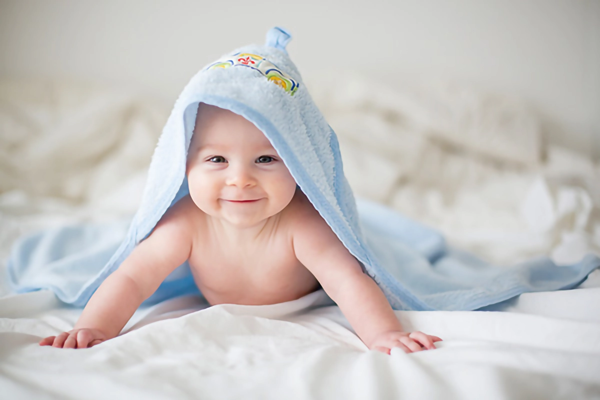 Image of a baby in a towel on a bed.